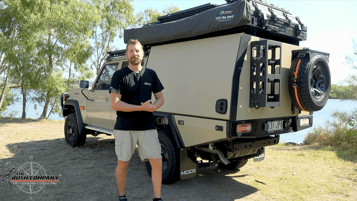 Man beside a Land Cruiser 79 Series touring rig with a rooftop tent and awning
