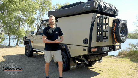 Man beside a Land Cruiser 79 Series touring rig with a rooftop tent and awning
