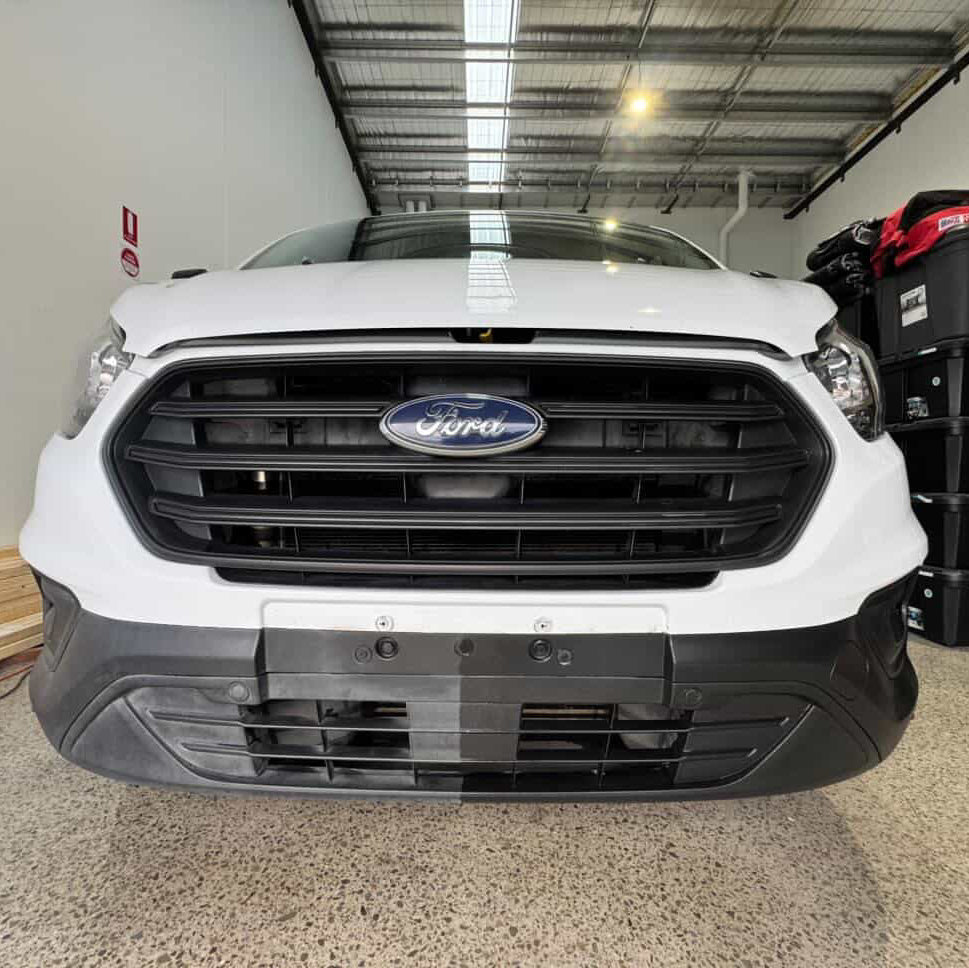 White Ford vehicle in a warehouse setting with storage bins in the background