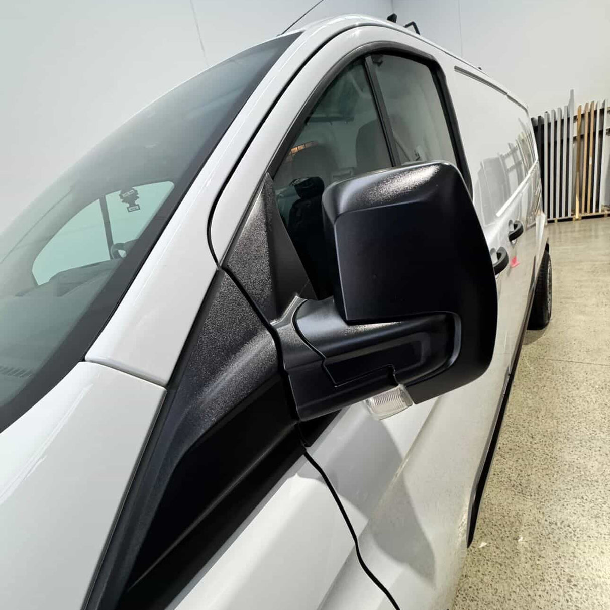Car side mirror with black cover on a white car