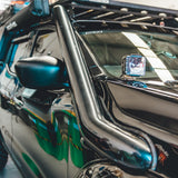 Close-up of a vehicle's side mirror and bumper with a reflective surface.
