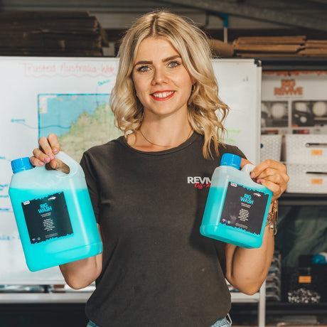 Woman holding two bottles of Revive wah fluid in a workshop setting