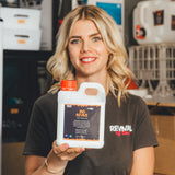 Person holding a bottle of 'Rig Revive' in a workshop setting