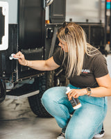 Person cleaning a vehicle with a black shirt and jeans in a garage setting